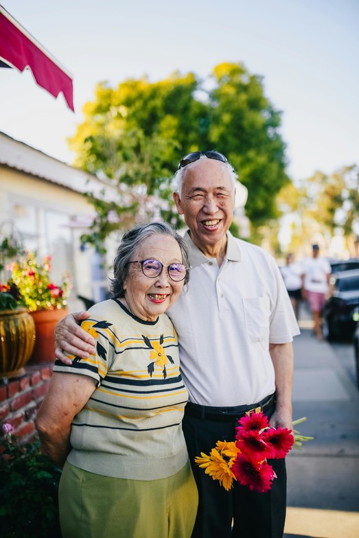 Elderly Asian Canadian couple enjoying a sunny day in their neighborhood. This image represents the love, connection, and caregiving relationships explored in our blog on filial piety, familism, and millennial caregiving in Ontario.